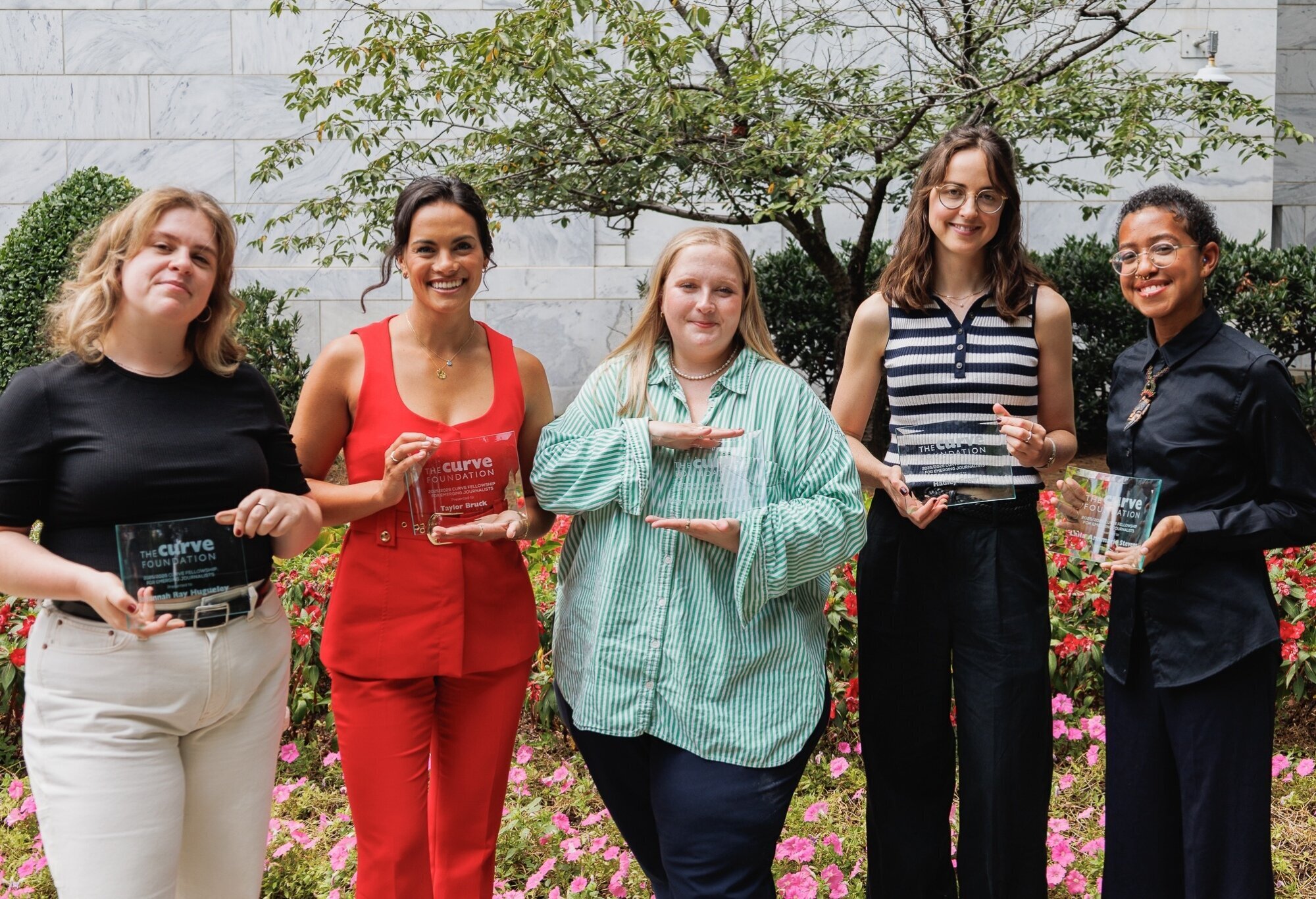 The recipients of the 2025-2026 Curve Fellowship for Emerging Journalists poses for the camera with their awards.