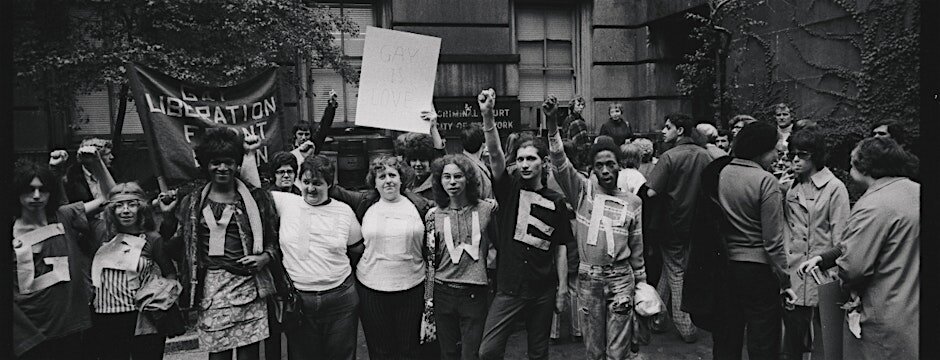 Fotografía de una manifestación LGTB. Las personas en primer plano llevan pegadas a la ropa las letras para decir "GAY POWER".