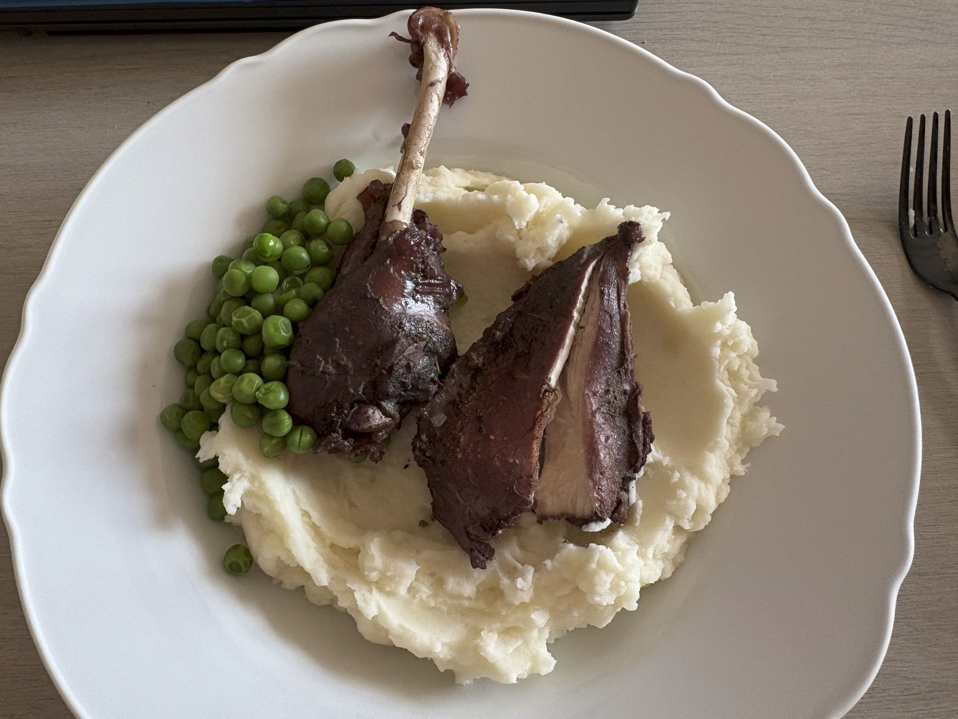 Coq Au Vin on mashed potatoes with a side of peas