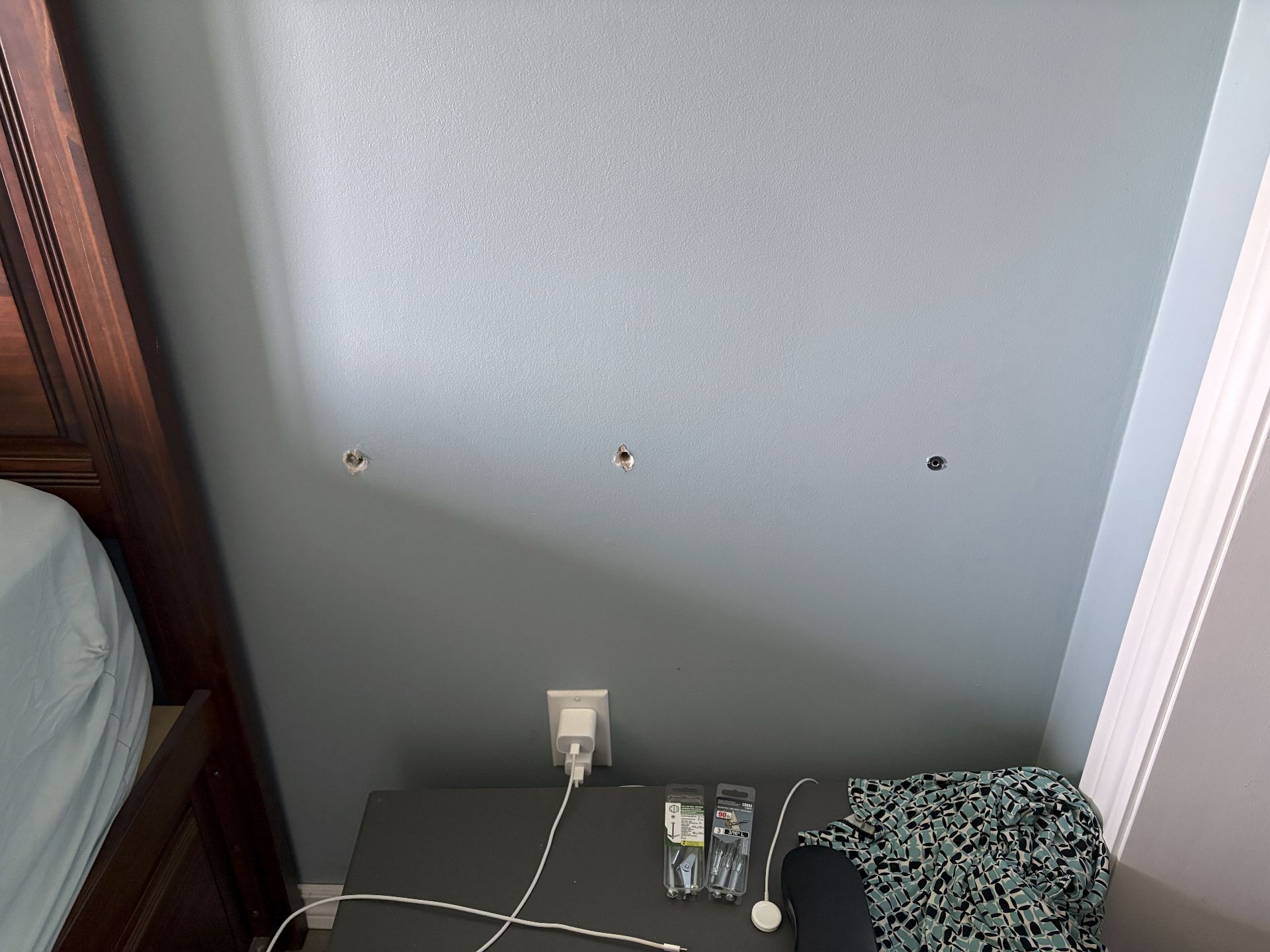 side table still on the floor with three holes in the drywall above it.