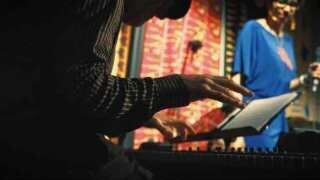 Image of Tom at the piano with Mama in background