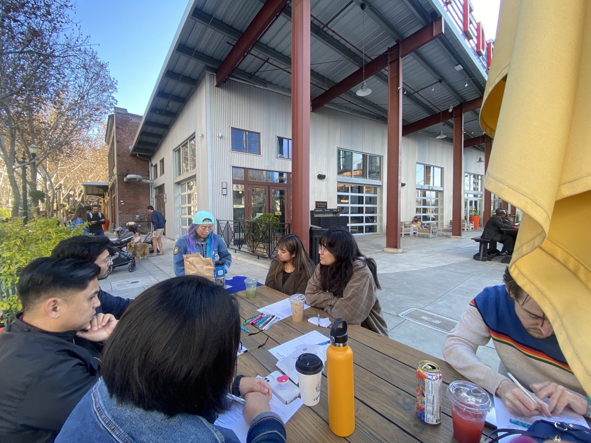 6 adults at a picnic table talking, listening, and taking notes