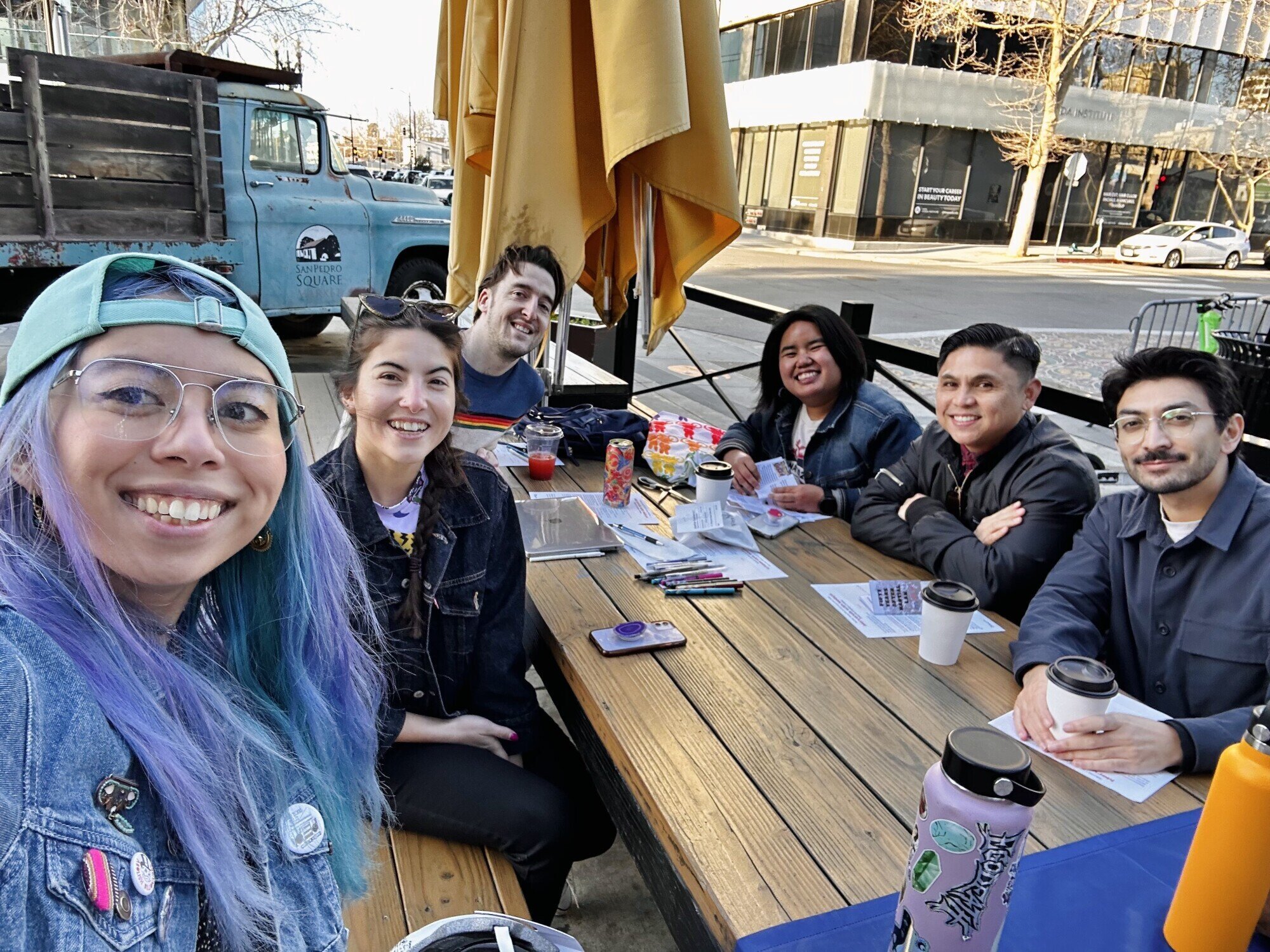 6 adults sitting at a picnic table smiling at the camera