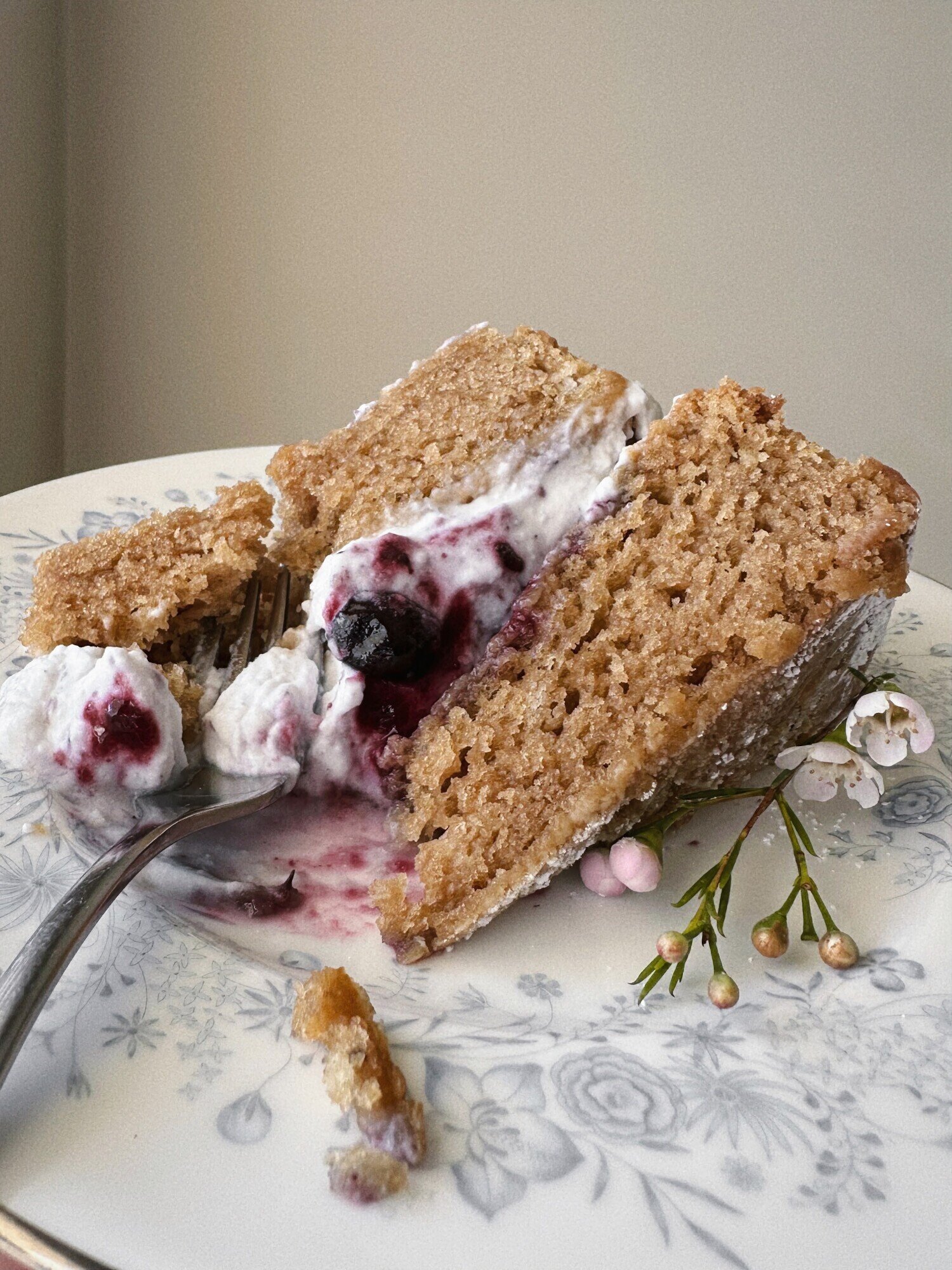 A 3/4 angle image shows a slice of earl grey olive oil cake with blueberry lavender compote and coconut whipped cream on a plate.
