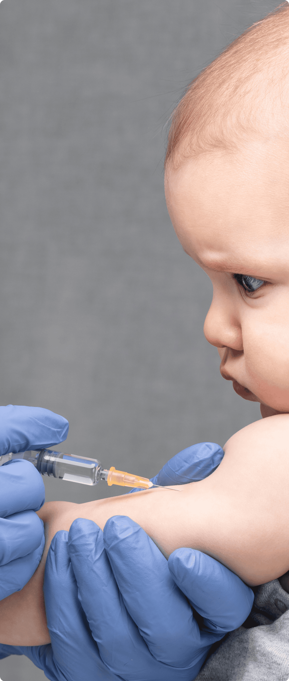 A healthcare professional in blue gloves administers a vaccine to a baby's arm.